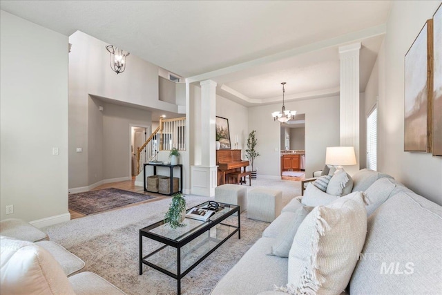 living room featuring ornate columns, carpet flooring, stairs, baseboards, and a tray ceiling