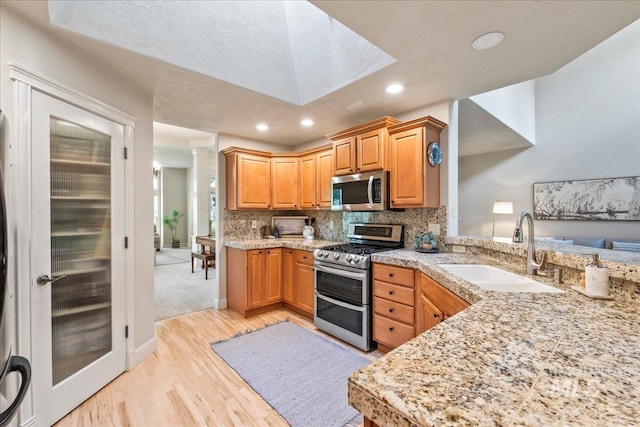 kitchen with stainless steel appliances, a sink, light wood-type flooring, ornate columns, and recessed lighting