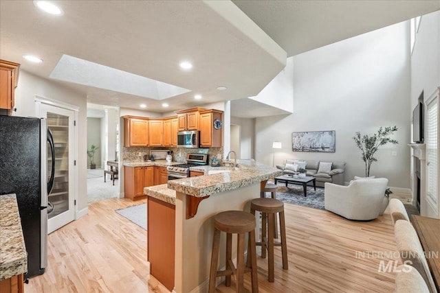 kitchen featuring stainless steel appliances, light wood-style floors, a breakfast bar, a peninsula, and open floor plan