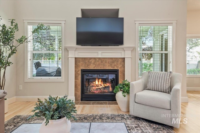 living area featuring wood finished floors, a tile fireplace, and baseboards