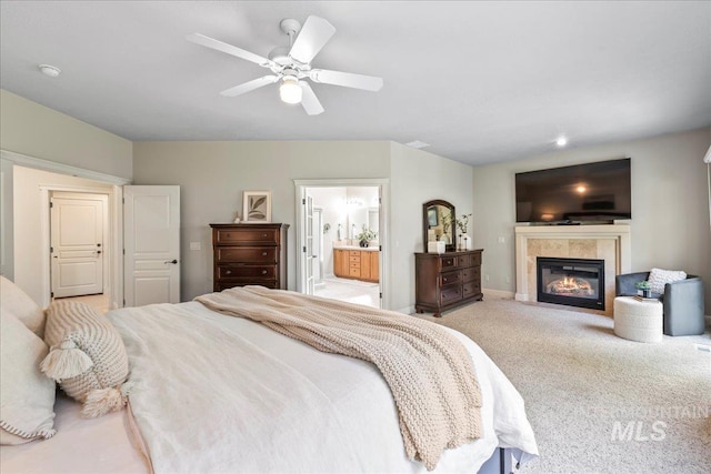 bedroom featuring a fireplace, carpet, connected bathroom, a ceiling fan, and baseboards