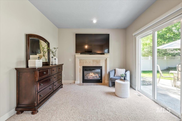 living area with light carpet, baseboards, and a tile fireplace