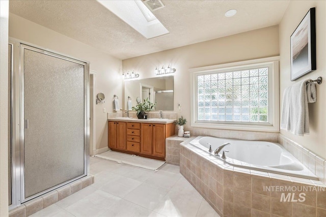 full bathroom with a skylight, a bath, double vanity, a shower stall, and tile patterned floors