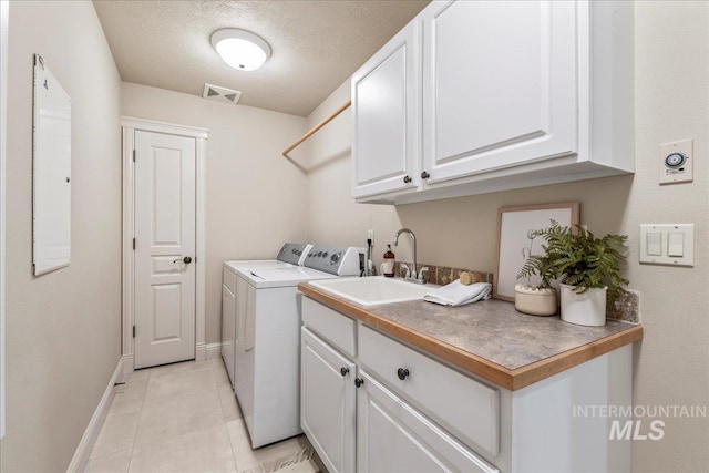 laundry room featuring independent washer and dryer, cabinet space, baseboards, a textured ceiling, and light tile patterned flooring