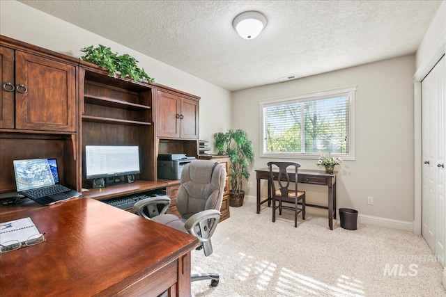 office with a textured ceiling, light colored carpet, and baseboards