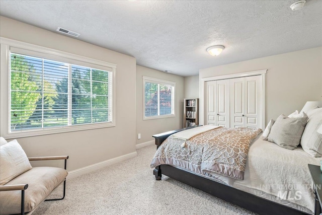carpeted bedroom featuring baseboards, a closet, and a textured ceiling