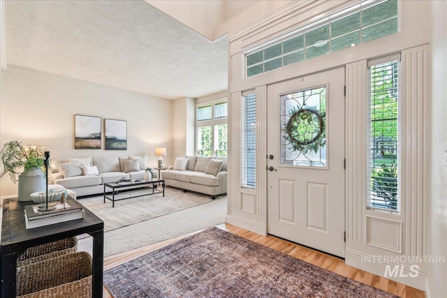 foyer entrance with wood finished floors and a textured ceiling