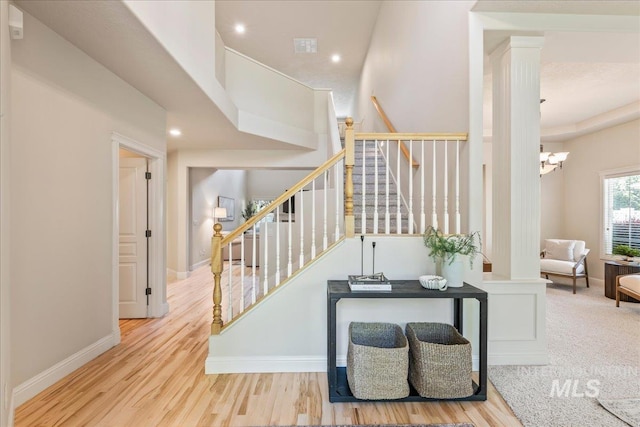 stairway featuring wood finished floors, baseboards, recessed lighting, a chandelier, and decorative columns