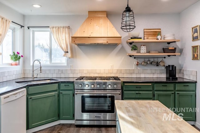 kitchen featuring high end stove, a sink, green cabinetry, custom exhaust hood, and dishwasher