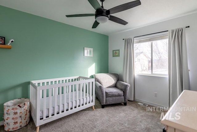 bedroom with carpet flooring, a nursery area, baseboards, and ceiling fan