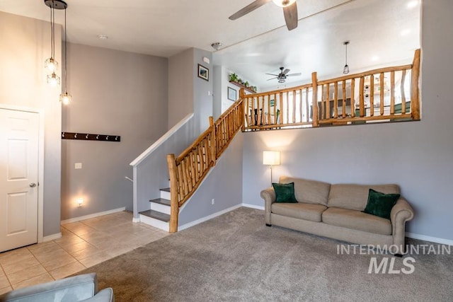 carpeted living room with baseboards, stairway, a towering ceiling, tile patterned floors, and a ceiling fan