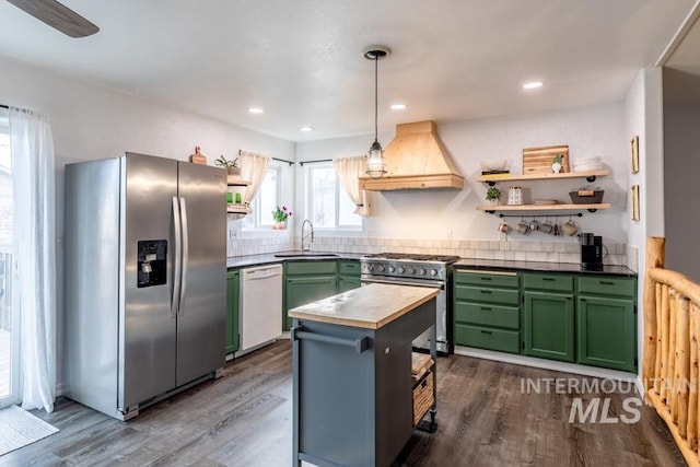 kitchen with premium range hood, open shelves, a sink, appliances with stainless steel finishes, and green cabinets