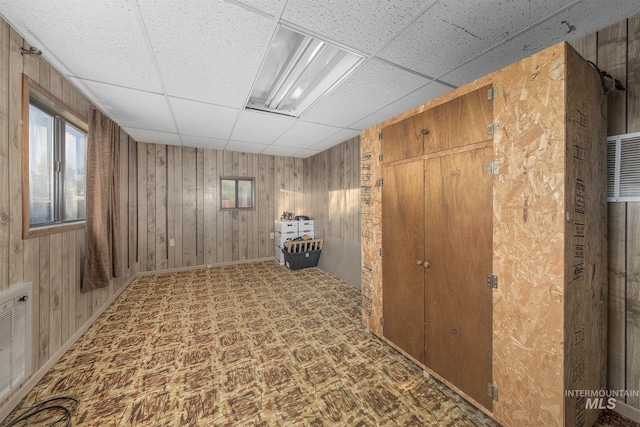 basement with wood walls and a paneled ceiling