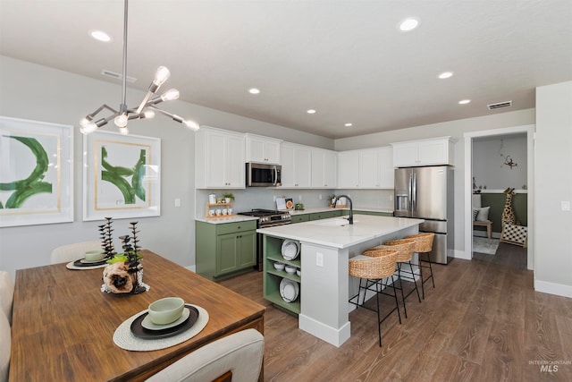 kitchen featuring green cabinetry, white cabinetry, hardwood / wood-style floors, and stainless steel appliances