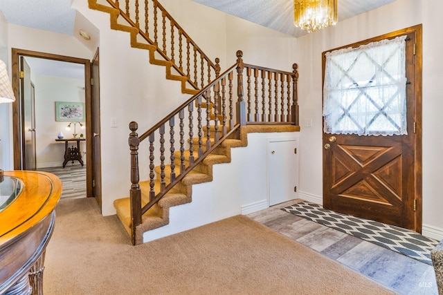 foyer with a chandelier, stairway, wood finished floors, and baseboards
