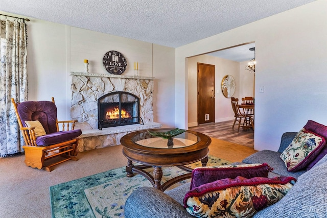 living room with a chandelier, a textured ceiling, a fireplace, and baseboards