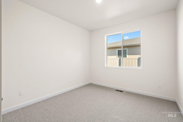 carpeted spare room with visible vents and baseboards