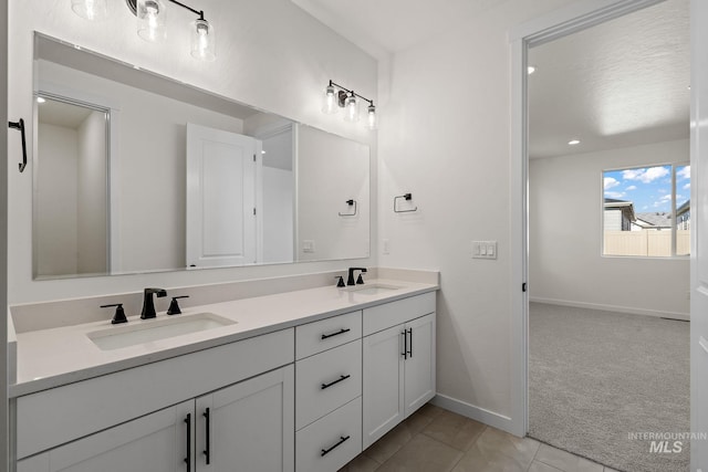 full bathroom featuring a sink, baseboards, double vanity, and tile patterned flooring