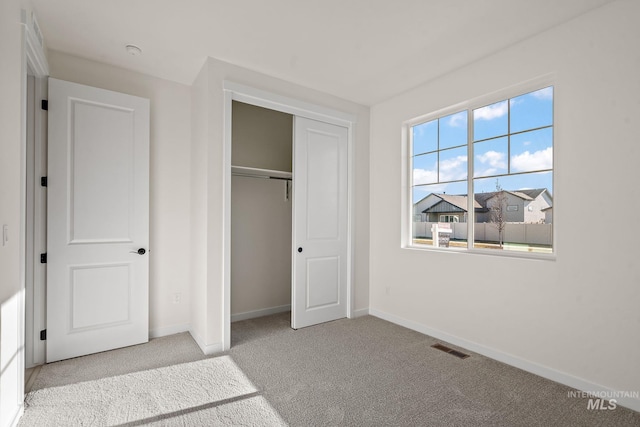 unfurnished bedroom featuring carpet, visible vents, a closet, and baseboards