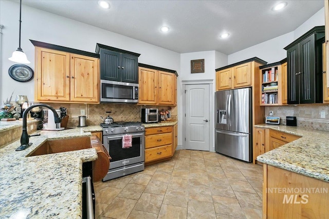 kitchen featuring hanging light fixtures, a sink, light stone countertops, appliances with stainless steel finishes, and decorative backsplash