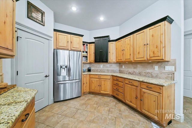 kitchen with stone finish flooring, light stone countertops, tasteful backsplash, and stainless steel refrigerator with ice dispenser