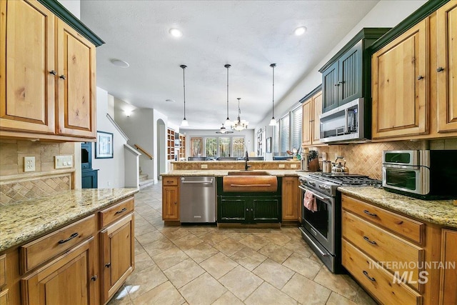 kitchen featuring a sink, a peninsula, stainless steel appliances, backsplash, and a notable chandelier