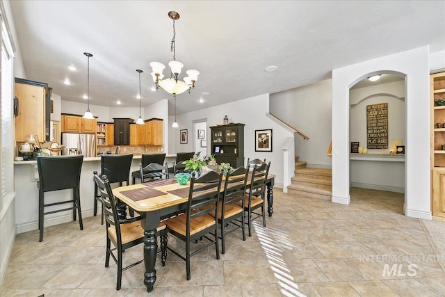 dining room with baseboards, stairway, stone finish flooring, and an inviting chandelier