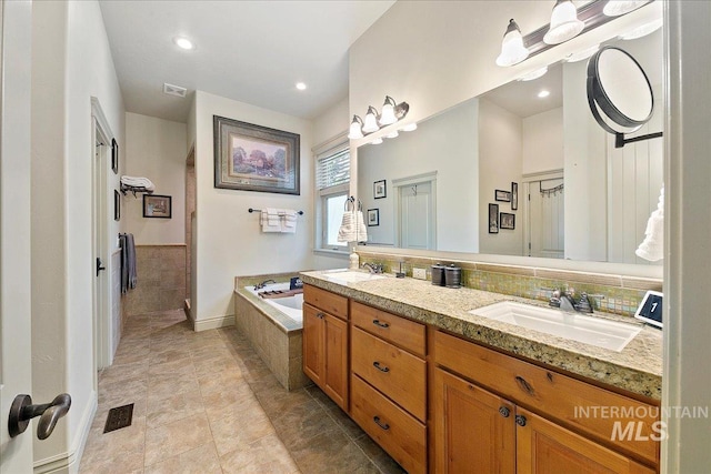 full bathroom with a garden tub, visible vents, a sink, and double vanity