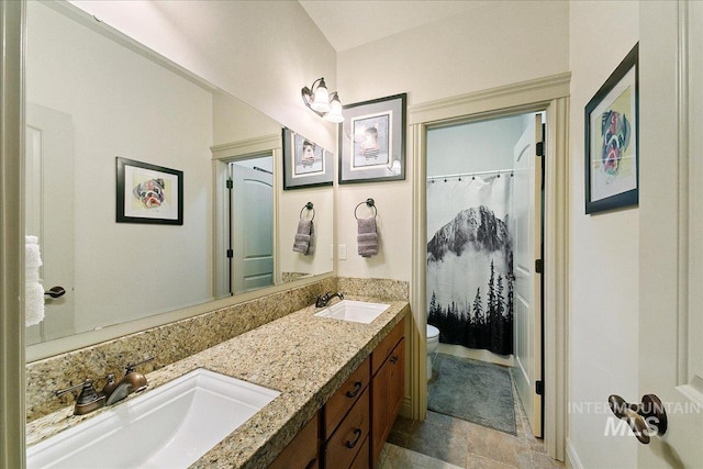 bathroom featuring toilet, a shower with curtain, double vanity, and a sink