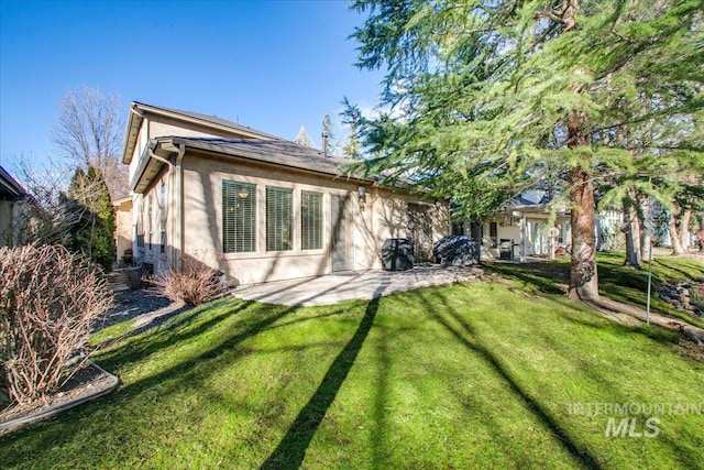 back of property with a yard, a patio, and stucco siding