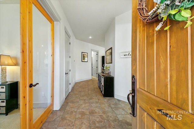hall with baseboards, stone finish floor, and recessed lighting