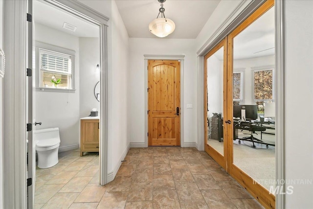 entrance foyer with french doors, baseboards, stone finish flooring, and a healthy amount of sunlight