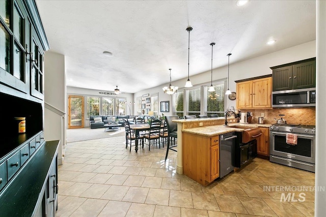 kitchen featuring recessed lighting, open floor plan, a peninsula, decorative backsplash, and appliances with stainless steel finishes
