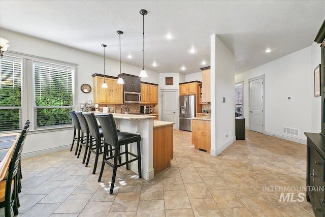 kitchen featuring a peninsula, tasteful backsplash, a breakfast bar area, pendant lighting, and appliances with stainless steel finishes