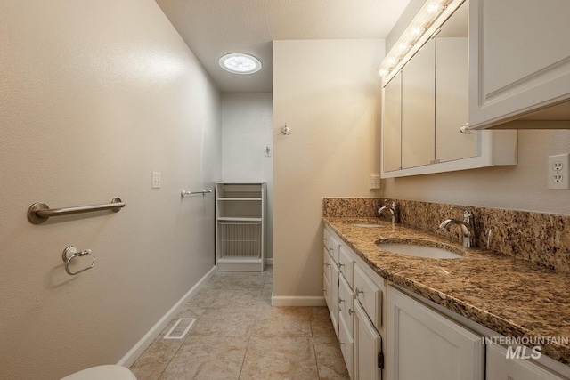 bathroom featuring visible vents, a sink, baseboards, and double vanity