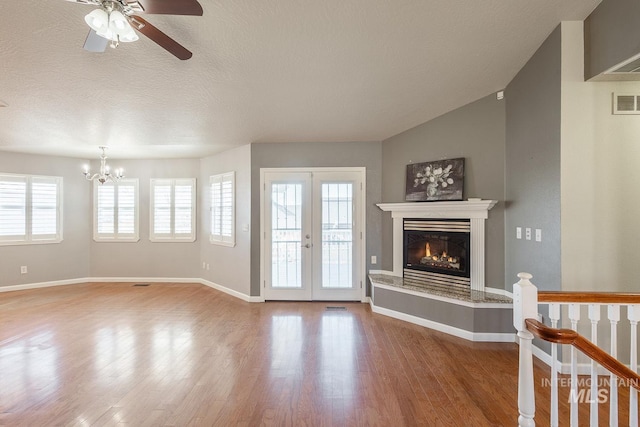 living room with a glass covered fireplace, a textured ceiling, baseboards, and wood finished floors