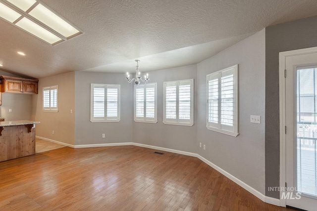 interior space with light wood-style floors, baseboards, a breakfast bar, and an inviting chandelier