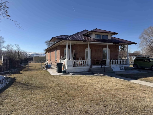 view of front facade featuring brick siding, a porch, a front lawn, and fence