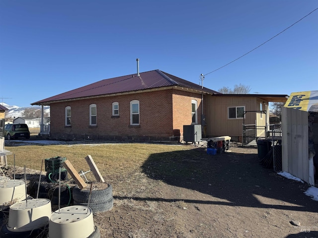 145 N Lincoln, Oakley, ID 83346 - rear view of house with central air condition unit, a yard, brick siding, and metal roof