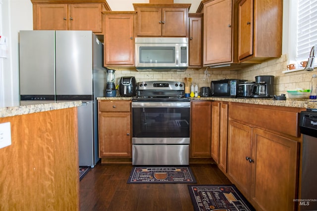 kitchen featuring appliances with stainless steel finishes, dark hardwood / wood-style flooring, backsplash, and light stone counters