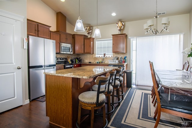 kitchen featuring tasteful backsplash, decorative light fixtures, stainless steel appliances, dark hardwood / wood-style flooring, and a center island