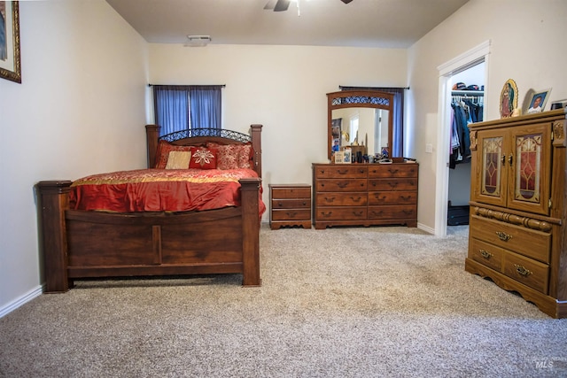 carpeted bedroom featuring a walk in closet, ceiling fan, and a closet