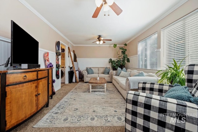 living room with ornamental molding, light colored carpet, wainscoting, and a ceiling fan