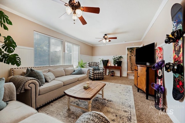 living area with wainscoting, carpet flooring, a ceiling fan, and crown molding