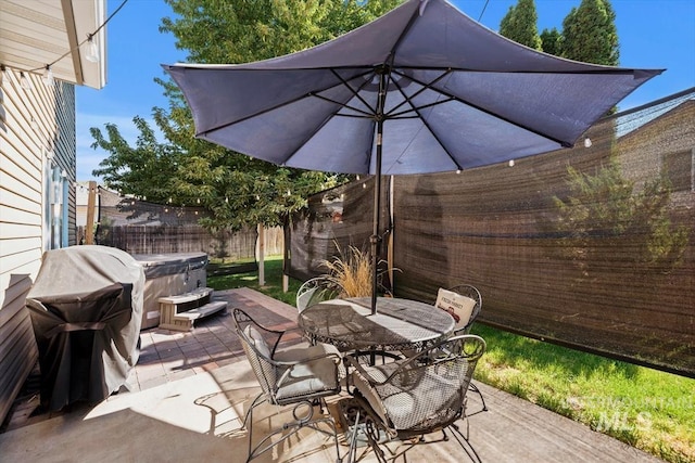 view of patio / terrace with outdoor dining space, a fenced backyard, and a hot tub