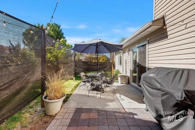 view of patio featuring outdoor dining space, a grill, and fence