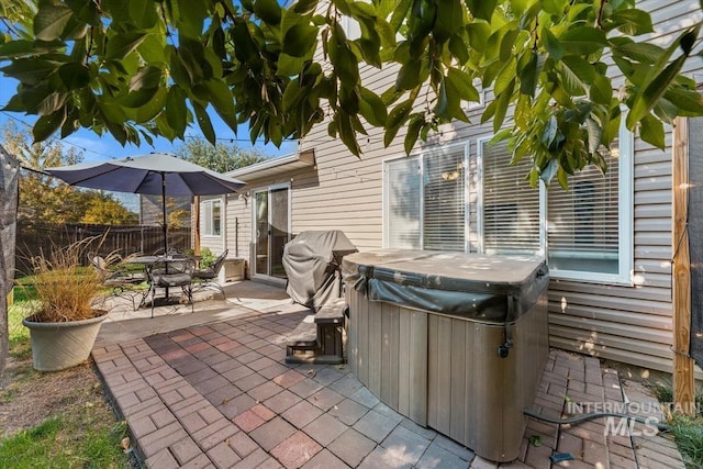 view of patio / terrace featuring outdoor dining space, fence, a hot tub, and grilling area