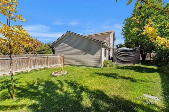 view of property exterior with an outdoor fire pit, fence, and a yard