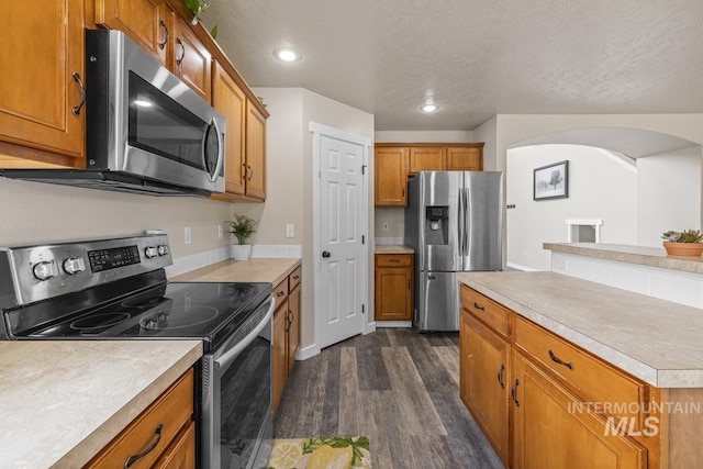 12339 W Foxhaven St, Star, ID 83669 - kitchen featuring stainless steel appliances, dark wood-style flooring, brown cabinets, light countertops, and recessed lighting