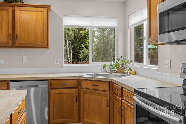 12339 W Foxhaven St, Star, ID 83669 - kitchen featuring appliances with stainless steel finishes, light countertops, brown cabinetry, and plenty of natural light